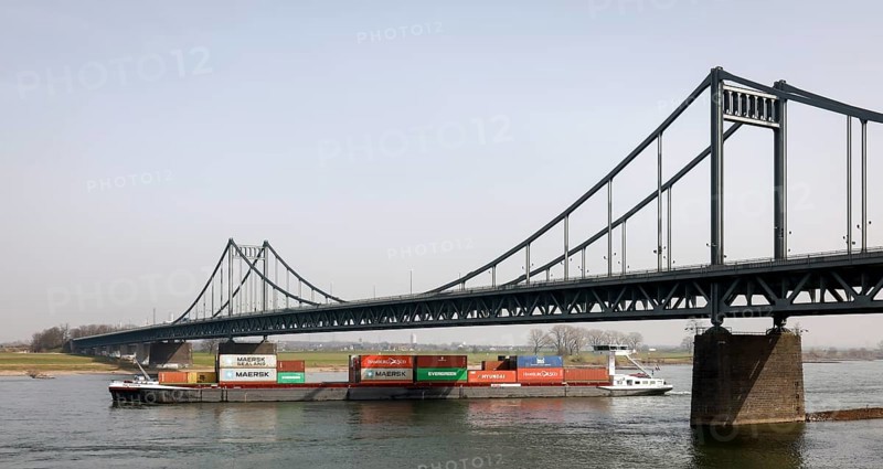 Krefeld, North Rhine-Westphalia, Germany - Cargo ship crosses the Rhine under the Krefeld-Uerdingen bridge at the Rhine harbour Krefeld