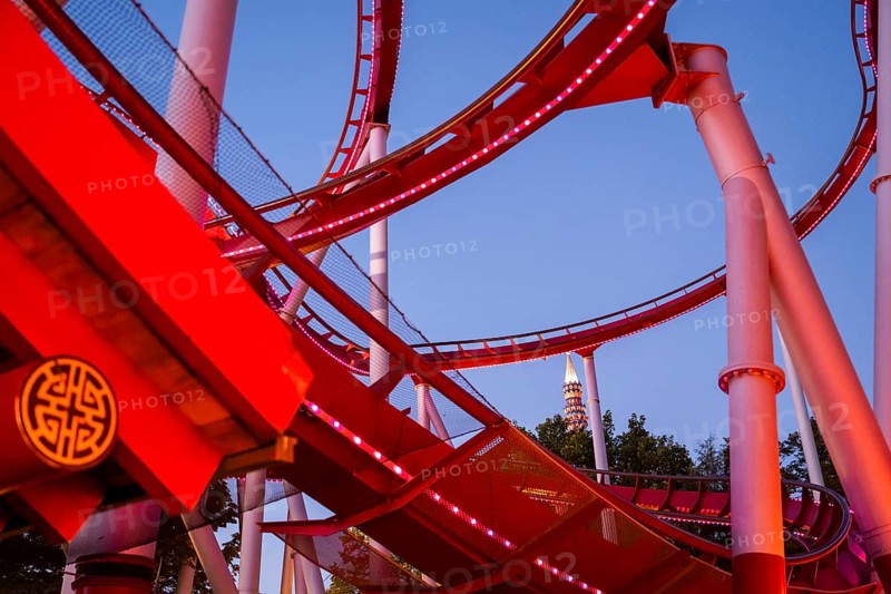 Red-lit roller coaster at dusk, Tivoli Amusement and Recreation Park, Copenhagen, Denmark, Europe