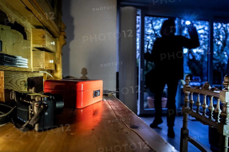 Symbolic image of a burglary, perpetrator has broken into a flat from the garden side and is looking for loot, cash box, valuables, money, technology