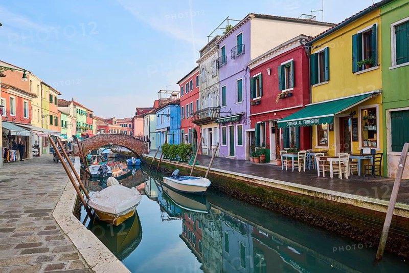Colorful houses and a bridge 'Ponte - Fondamenta San Mauro' going over the waterway with boats lying in the water on the island of Burano, Italy, Europe