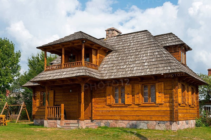 Traditional, light brown wooden house with veranda surrounded by sunshine, Bialowieza, Bialowieza, Podlaskie Voivodeship, Podlaskie, Poland, Europe