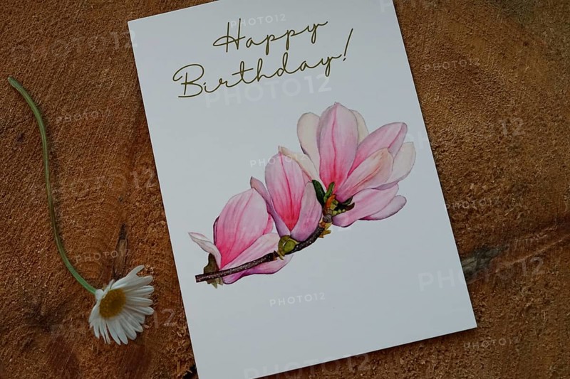 Happy Birthday card with a magnolia branch painted in watercolour, card as product photo for sale on Etsy, decorated on a tree slice, a daisy at the bottom left