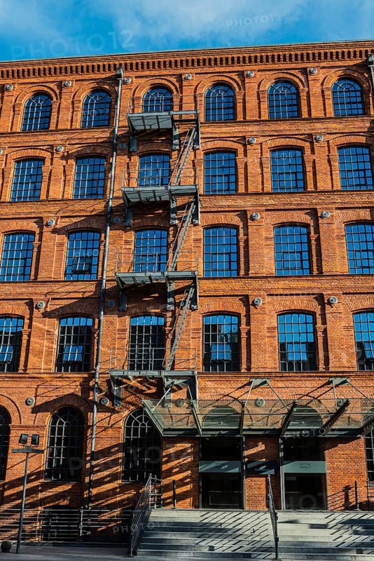 Facade of a brick building with rows of windows and shadows from a staircase, Manufaktura, Lódz, Lodz, Lodz, Poland, Europe