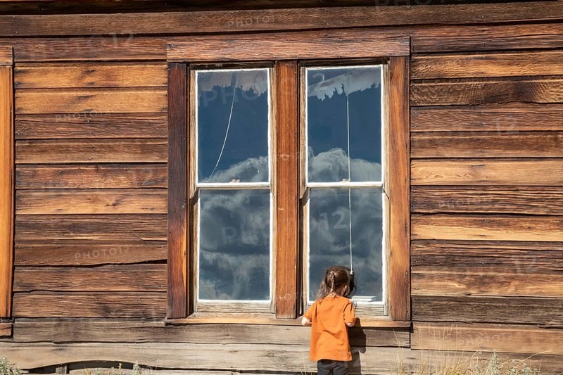 Bodie, California - A child looks in the window of the old schoolhouse at Bodie State Historic Park. The park preserves the remains of a gold mining town that once had a population of 8, 500 people