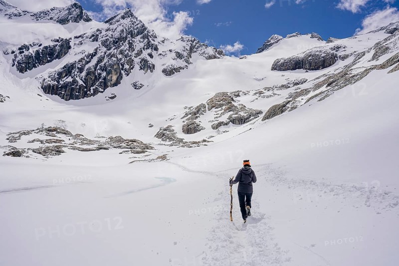 Woman hikes across a snowfield, Glaciar Vinciguerra, Ushuaia, Tierra del Fuego Province, Argentina, Person beim Wandern in einer verschneiten Berglandschaft unter klarem Himmel, Argentinien, South America
