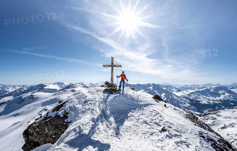 Ski tourer at the summit of Monte Cevedale with summit cross, sun star, mountain panorama, snow-covered mountain landscape in winter, Ortler Alps, Vinschgau Valley, Italy, Europe