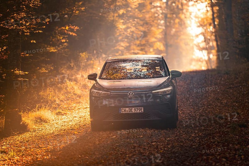 Car driving on a forest path covered with leaves on a sunny autumn day, electric car VW ID5, Gechingen, Black Forest, Germany, Europe