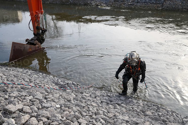 Dinslaken, Voerde, North Rhine-Westphalia, Germany - New Emscher estuary into the Rhine. Restoration of the dykes after dyke erosion during the 2023 flood. Shoring of gabions, stone baskets on the riverbank. Industrial divers secure the gabions, connect the stone baskets under water with metal cable ties. Renaturalisation of the Emscher. Flood protection by expanding the area. The mouth of the Emscher into the Rhine has been moved almost 500 metres north from Dinslaken to Voerde. Fish can now swim barrier-free up the new Emscher from the Rhine through a newly created floodplain area. Following the construction of a parallel sewer, the Emscher has been completely free of sewage since January 2022. The river was previously an open, above-ground combined sewer with rainwater and wastewater