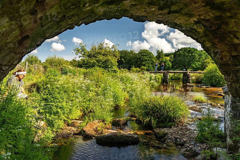 Tourists on the medieval stone slab bridge Clapper Bridge in Postbridge, Dartmoor, Devon, England, Great Britain