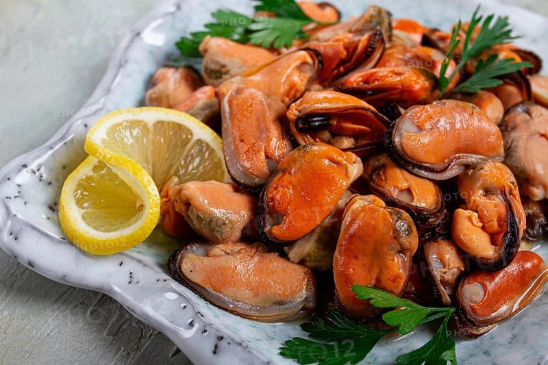 Mussels no shell, boiled, mussels, peeled, in a bowl, with lemon and parsley, Chilean mussels, top view, no people