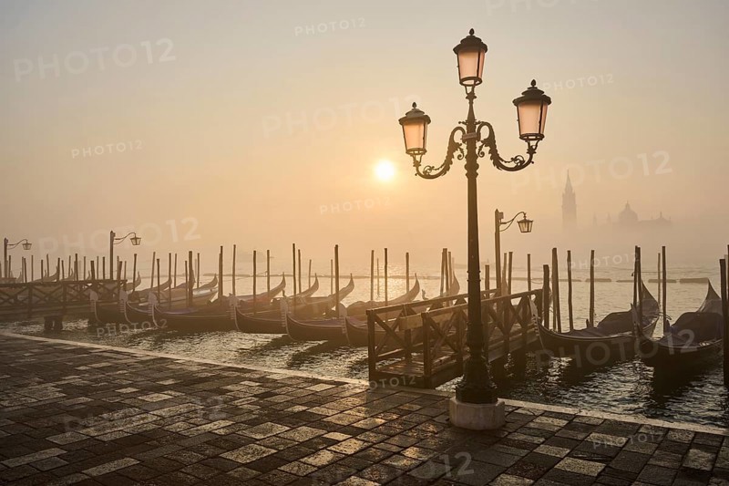 View from 'Colonna di San Marco e San Teodoro' on a latern and the gondolas lying in the water with the church 'Giorgio Maggiore' in the background at sunrise in Venice on a foggy morning in winter, Italy, Europe
