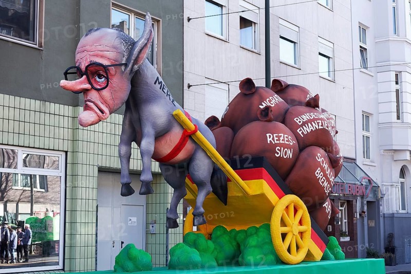 Chancellor candidate Friedrich Merz as a donkey figure in front of a cart with heavy sacks, debt brake, recession, migration, papier-mâché figure, theme float by Jacques Tilly, Rosenmontagszug 2025, Düsseldorf, Rhineland, North Rhine-Westphalia, Germany, Europe