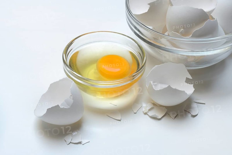 Egg whites and egg yolks in glass bowl and egg shells, whisk