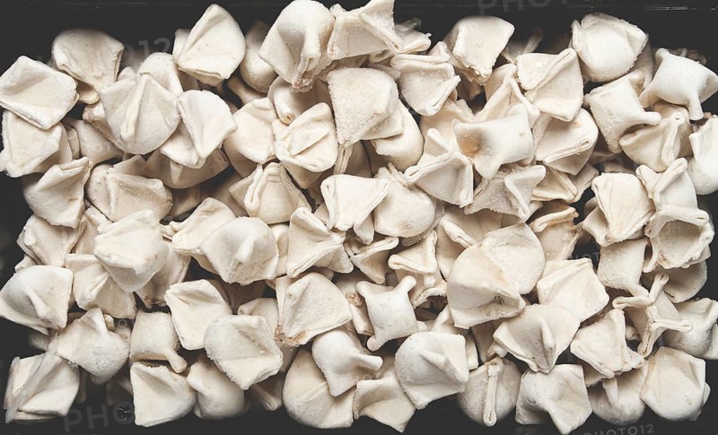 Traditional Turkish dumplings, raw, in a black container, top view, no people