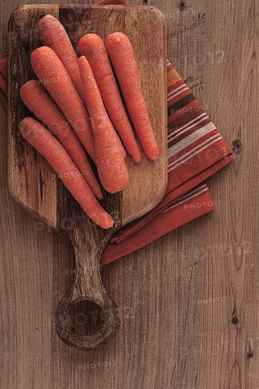 Fresh carrots on a chopping board, wooden table, raw carrots, no people