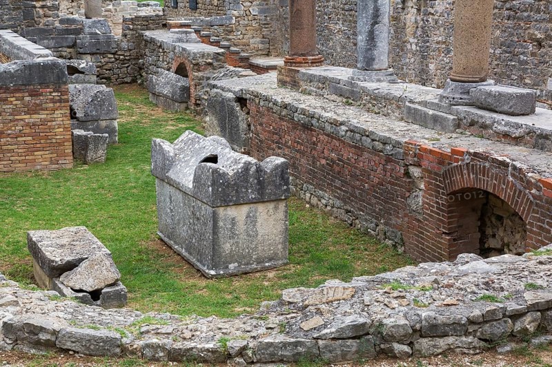 High angle view of old semi circle grey stone structure, terracotta brick wall and columns at ancient 3rd century Roman ruins of Salona near Solin in late summer, Croatia, Europe