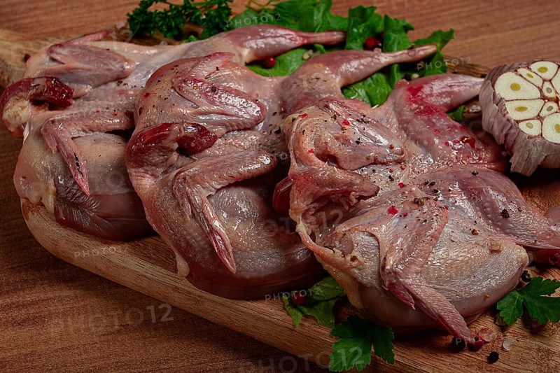 Raw quail meat, on a cutting board, with spices and herbs, top view