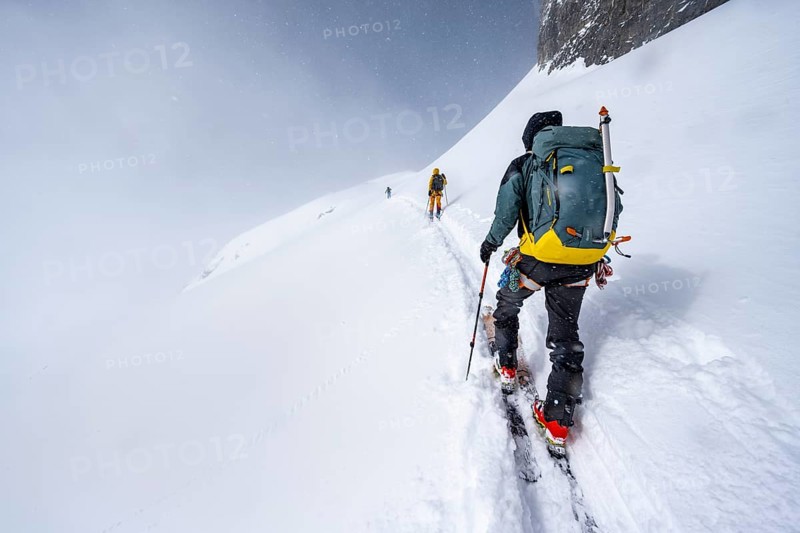 Three ski tourers in a snowy mountain landscape, ascent to the Wildhorn, cloudy mood, high tour, Bernese Alps, Bernese Oberland, Switzerland, Europe