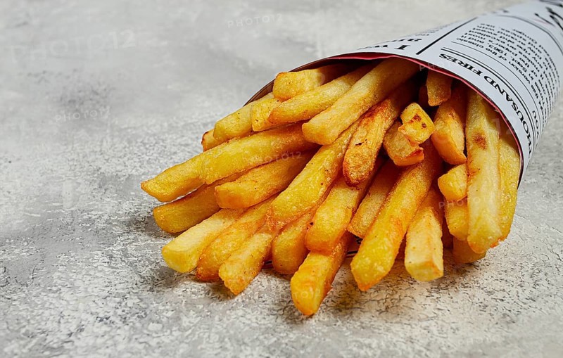 Fried French fries in a paper bag, on an abstract background, without people, in a rustic style, in a cone package, newspaper, a bag from the newspaper