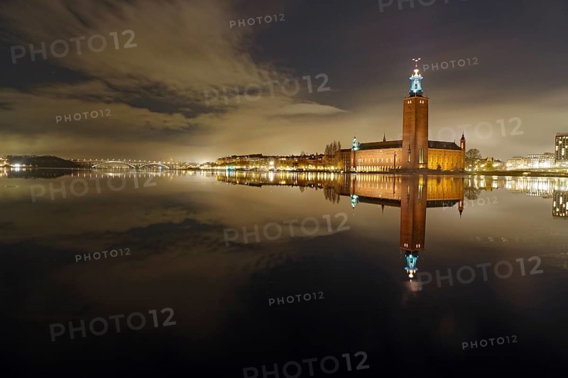 Night shot of an illuminated city building on the shore with reflection in the water, winter, ice, capital, city hall, Stadshus, Nobel Prize, Stockholm, Sweden, Europe