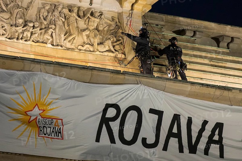 Police officers from the High Altitude Rescue Team remove a banner with the inscription For Democracy in Syria / Defend Rojava from the Brandenburg Gate, Berlin, 16 December 2024
