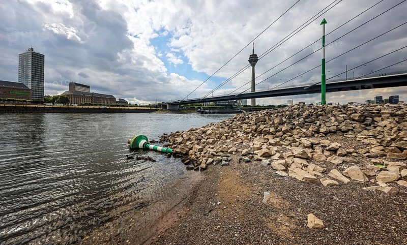 Düsseldorf, North Rhine-Westphalia, Germany, Overturned fairway buoy at low water in the Rhine in front of the Rhine knee bridge and Rhine tower. After a long dry spell, the water level in the Rhine fell to 71 cm today. Skippers speak of low water at this level, Europe