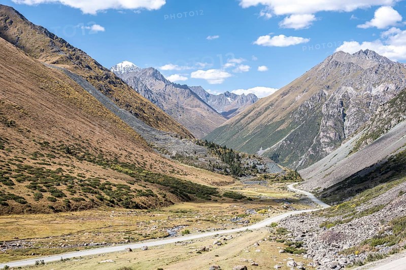 Gravel track in a valley, picturesque mountain landscape with white mountain peaks, Tian Shan Mountains, Issyk-Kul, Kyrgyzstan, Asia