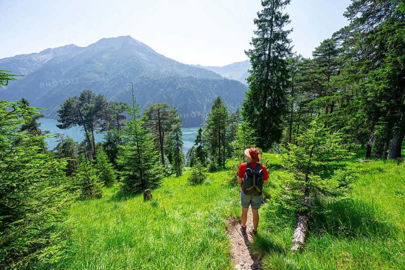Mountaineers descending through green coniferous forest, view of Lake Achensee with Seekarspitze peak, Unnütz crossing, Brandenberg Alps, Tyrol, Austria, Europe
