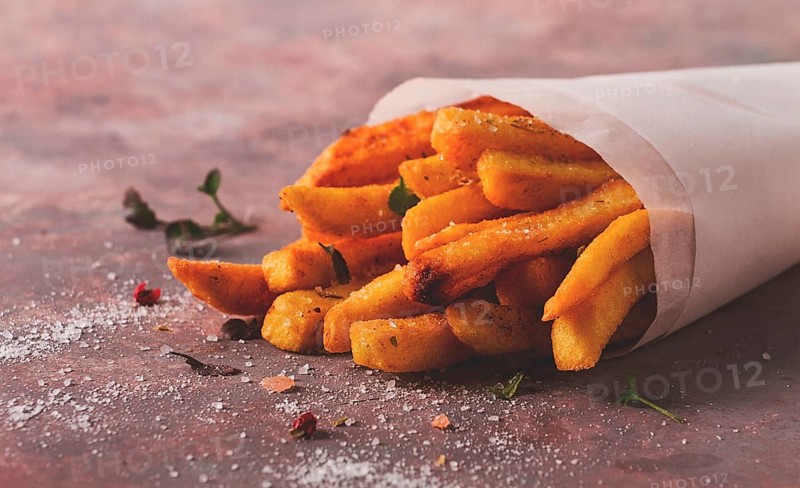 Fried French fries, in a paper bag, on an abstract background, no people, rustic