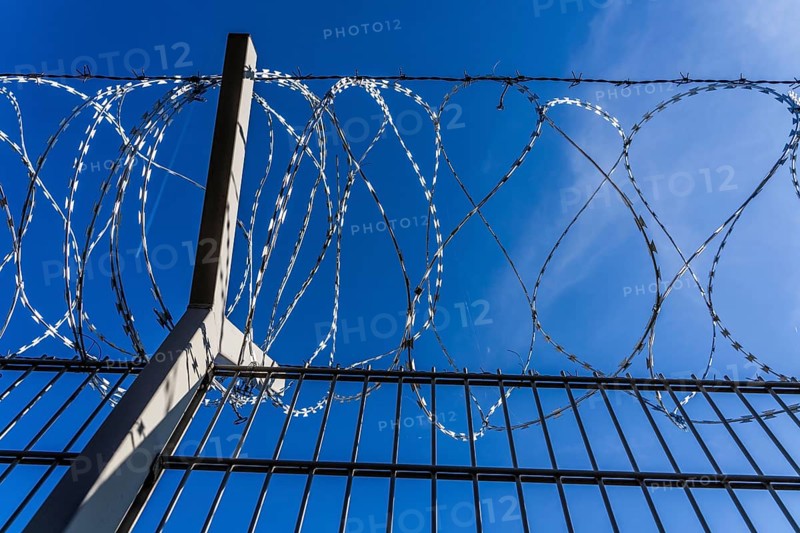 Symbolic image security, S-wire rolls, NATO wire, on a fence top, demarcation of a property, prevention of unauthorised access, strip steel wire with sharp blades