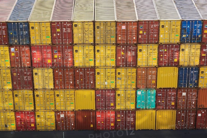 High angle view of stacked yellow and reddish brown MSC, TEX and CAI metal box shipping containers on dock in La Spezia cargo Port, Italy, Europe