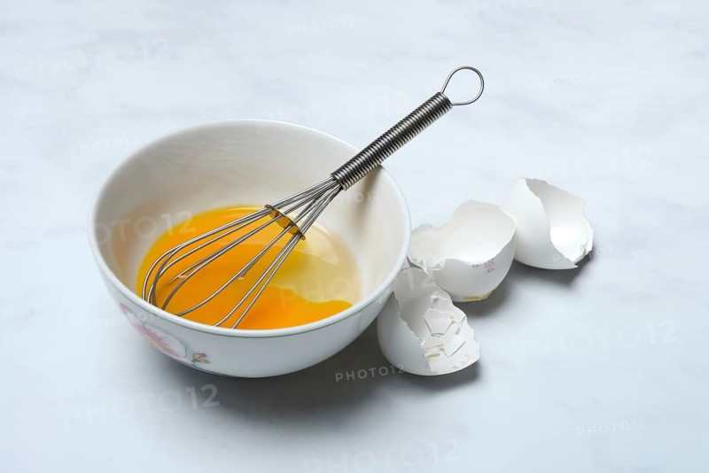 Whipped egg in shell with whisk, egg shells