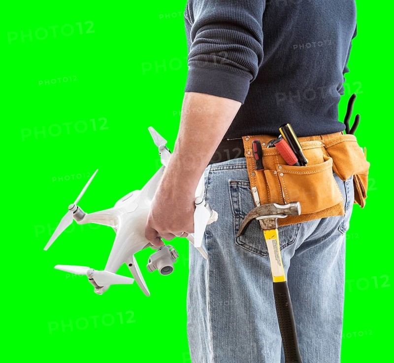 Partial view of construction worker wearing toolbelt and holding his UAV drone on green screen