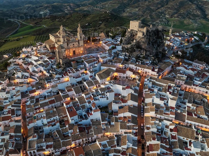 The hilltop White Town of Olvera with its La Encarnación church and Moorish castle. At dusk. Aerial view. Drone shot. Cádiz province, Andalusia, Spain, Europe