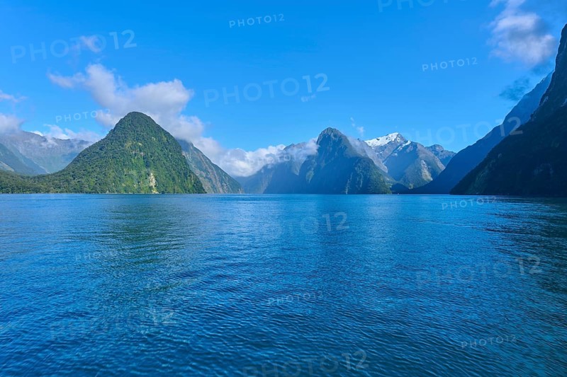Expansive water surface against a majestic mountain backdrop and blue sky, summer, Milford Sound, Te Anau, Fiordland National Park, South Island, New Zealand, Oceania
