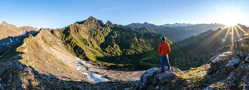 Mountaineer in front of mountain landscape at sunrise, sun star, view of mountain peaks of the Venediger group and into the Großbachtal valley from the summit of Bachlenkenkopf, Lasörling group, Hohe Tauern National Park, East Tyrol, Tyrol, Austria, Europe