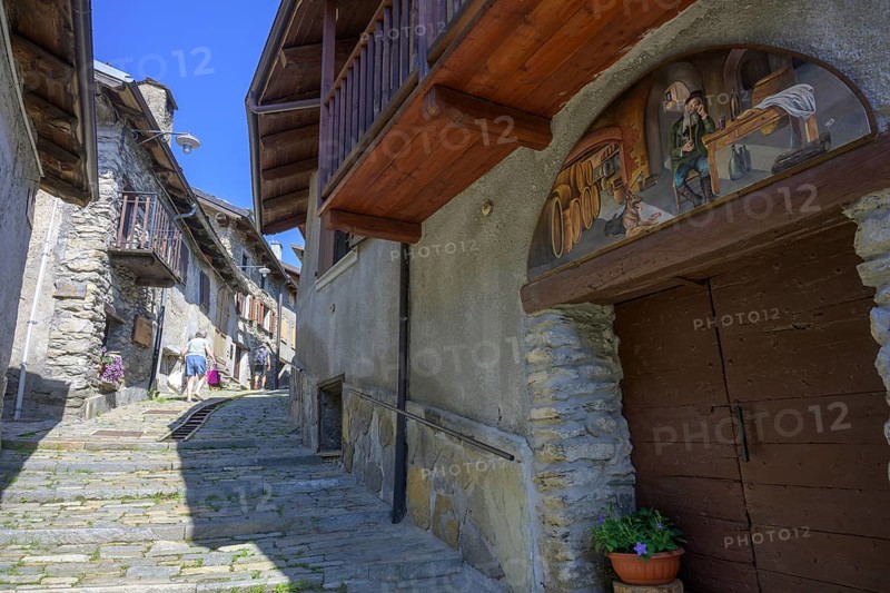 Pictures on the house walls characterise the narrow streets with old houses in the village, Usseaux, metropolitan city of Turin, Italy, Europe