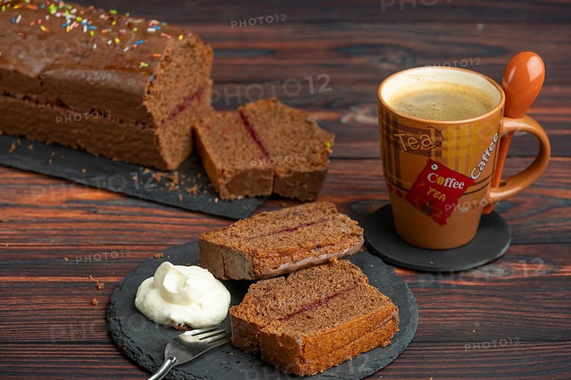 Several slices of chocolate cake with whipped cream on a plate, next to a cup of coffee