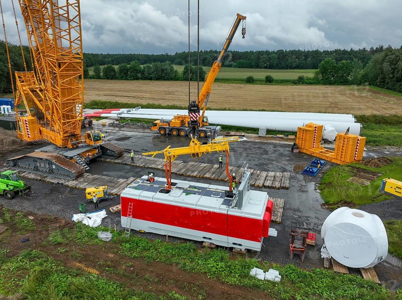 Dorsten, North Rhine-Westphalia, Germany, construction of a wind turbine, the first wind turbine of the Große Heide wind farm. A large mobile crane places the nacelle, the nacelle on the tower. The rotor blades, vanes and rotor hub are ready for assembly, Europe