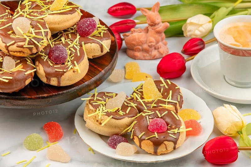 Decorated donuts next to coffee cup, Easter bunny, red tulips