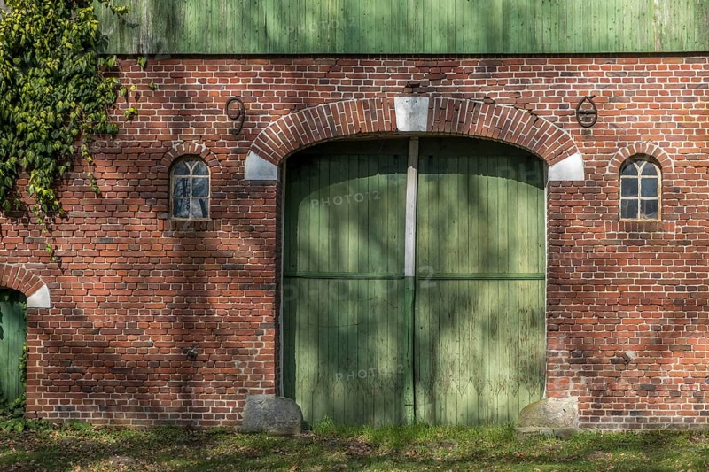 A brick wall with a large green barn door and two small windows, farmhouse, Münsterland, North Rhine-Westphalia, Germany, Europe
