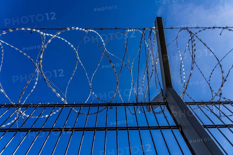 Symbolic image security, S-wire rolls, NATO wire, on a fence top, demarcation of a property, prevention of unauthorised access, strip steel wire with sharp blades