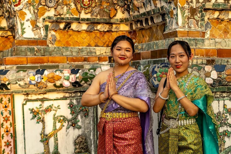 Traditionally dressed woman pose in front of the temple Wat Arun or Temple of Dawn in Bangkok, Thailand, Asia