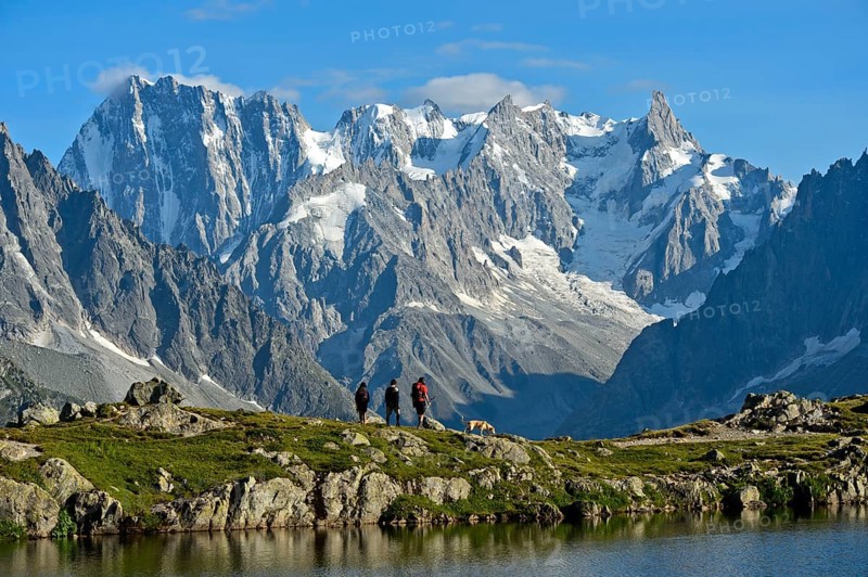 Hikers at the mountain lake Lacs des Chéserys in the Aiguilles Rouges nature reserve against the impressive backdrop of the Grandes Jorasse peaks, Chamonix, Haute Savoie, France, Europe