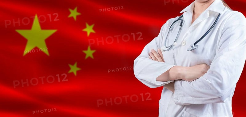Doctor with crossed arms on China flag. China Health and Care concept. Female doctor on China flag