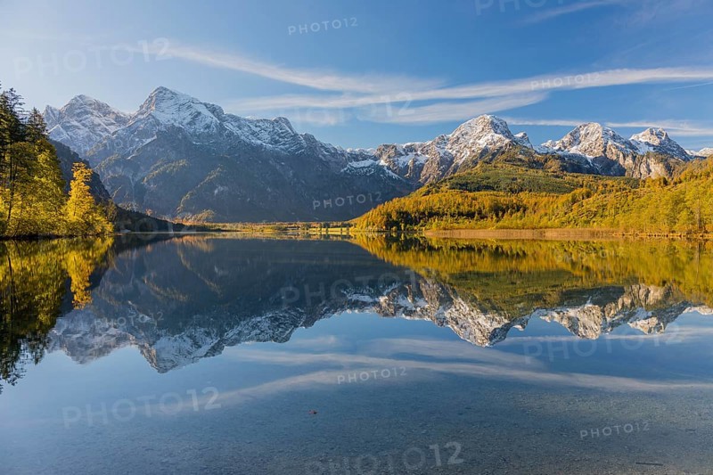 Lake Almsee in autumn with mountains reflected in the lake. Blue sky