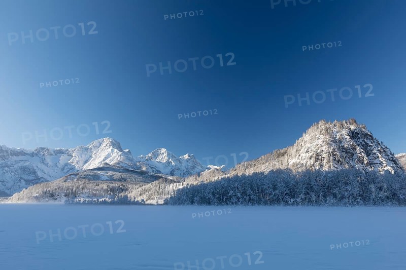 Ameisstein (776 m) mountain at the Lake Almsee in winter. The lake is frozen and snow covered, clear blue sky