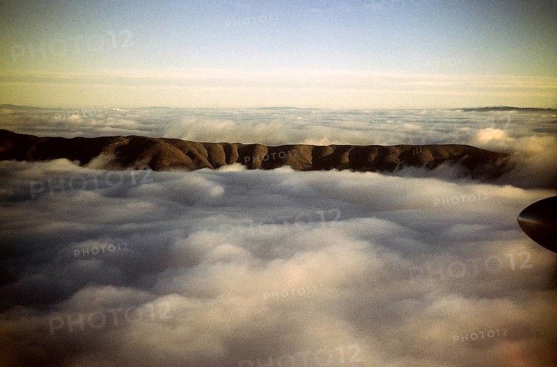Oblique view of a mountain ridge emerging from the cloud cover, location unknown, Australia 1956