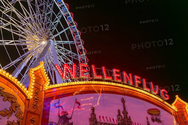Luminous merry-go-rounds and a Ferris wheel at night at a funfair, Europa Rad, rides, wave flight, Cannstatter Wasen, folk festival, Bad Cannstatt, Stuttgart, Baden-Württemberg, Germany, Europe