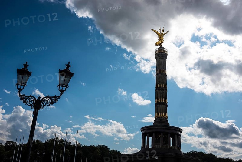 Victory Column next to an old street lamp in a dramatically cloudy sky with balu areas, towering column with angel figure, angel, bronze sculpture, bronze, looking into the light, symbol of hope, confidence despite distress, fear or darkness, Victory Column on the Great Star with gilded, winged goddess of victory Victoria (artist: Friedrich Drake), in Berlin vernacular also Goldelse, national monument, sight, Großer Tiergarten, Berlin Mitte, City of Berlin, Germany, Europe